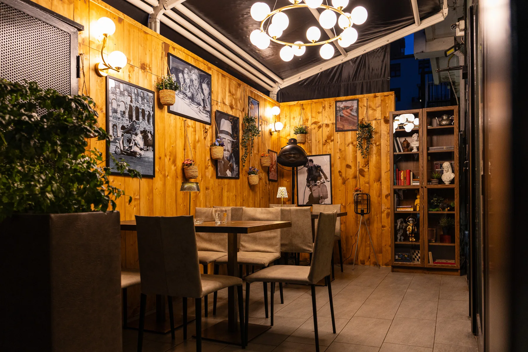 Angolo della sala con pareti in legno, piante e lampadario