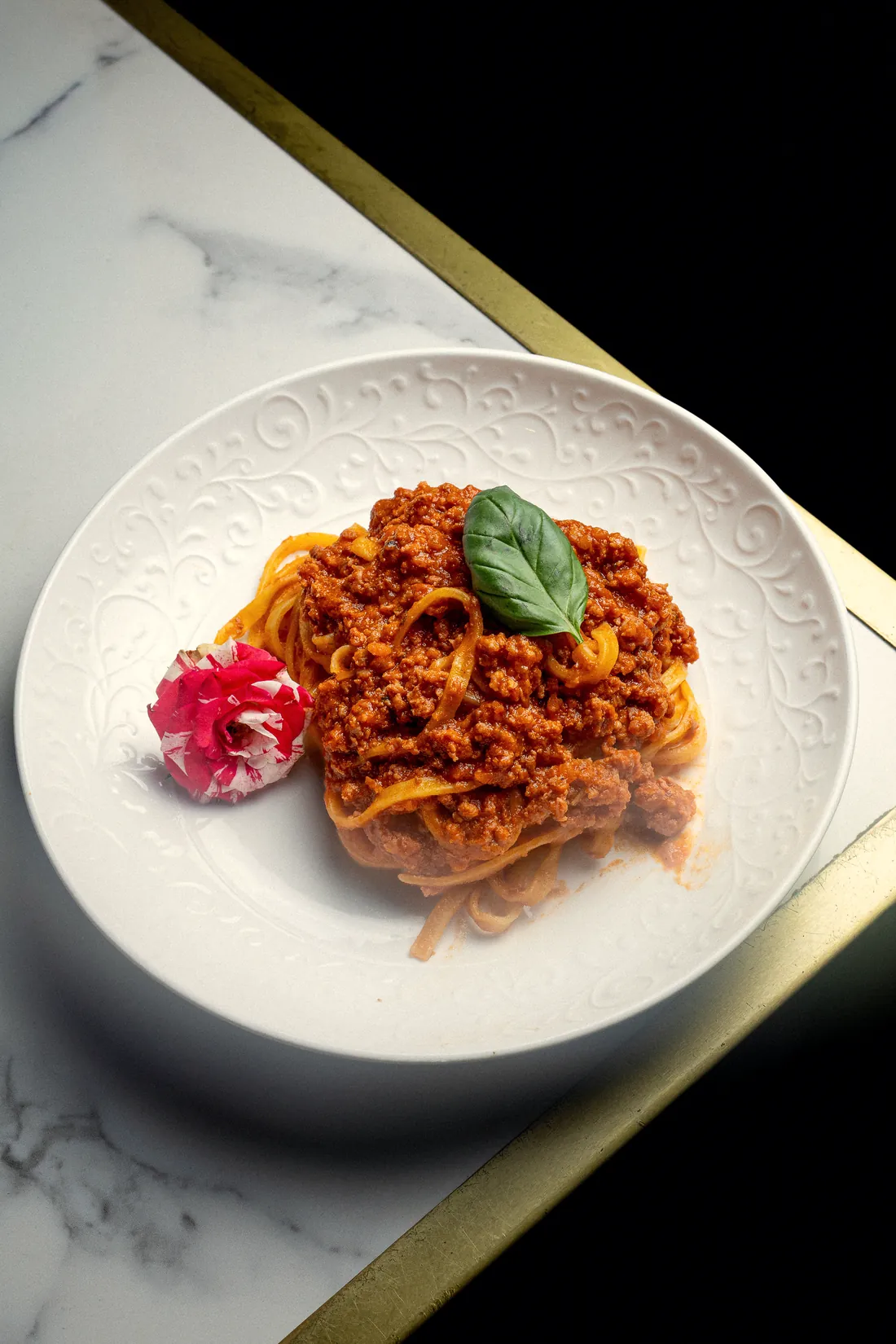 Tagliatelle al ragù con basilico su un piatto bianco